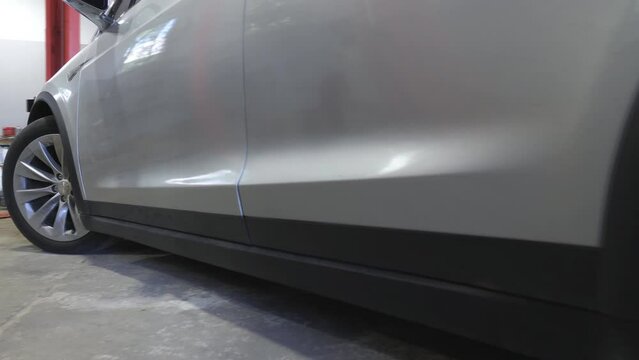 Close up of modern electric car driving into the garage for repairs. Electrical SUV vehicle riding into workshop. Concept of transportation service. Slow motion