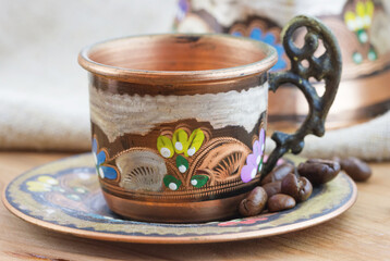 Old vintage traditional copper cup with roasted coffee beans and sackcloth on wooden table