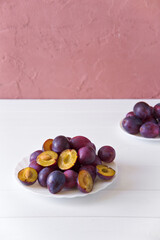 Fresh ripe plum cut in half in a plate with pits.