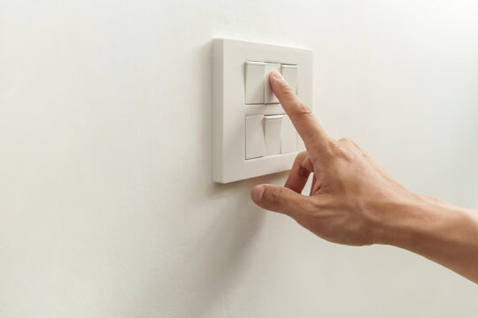 Closeup of finger is turning off on main control lighting switch on white wall at home. Power, Energy, Saving Electrical, Copy space.