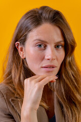 Portrait of attractive blue-eyed woman on a yellow background in a brown jacket