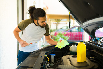 Young man checking the car oil
