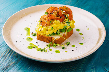 Scrambled eggs with avocado and shrimps on plate
