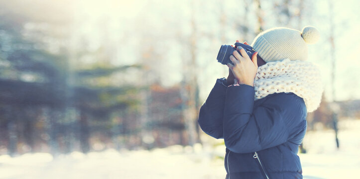 Child boy photographer with camera taking picture forest landscape in snowy winter park