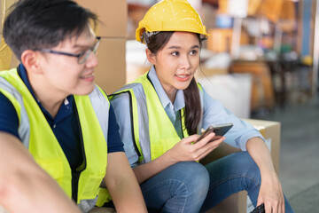 Staff in large storage warehouse together sit back relax funny laughing check mobile phone