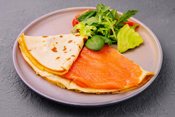 Pancake with red fish fillet on plate
