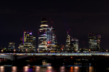 Fototapeta na wymiar Beautiful view of London city landscape from Thames waterfront at night, handheld shot. Rapid growth and urban development concept.