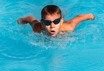 Boy swimmer swimming butterfly stroke in pool in action. Young athlete swim in swimming pool,...