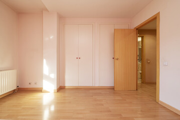 Empty room with white wooden door twin built-in wardrobes, light wooden door and laminated flooring
