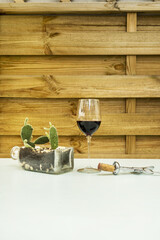 Flowerpot with opuntia microdasys with two new shoots, a corkscrew on a terrace with a wooden lattice and a glass of Spanish red wine