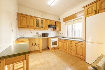 Fototapeta na wymiar Kitchen with Castilian-style wooden furniture with a table with a gray top and integrated appliances