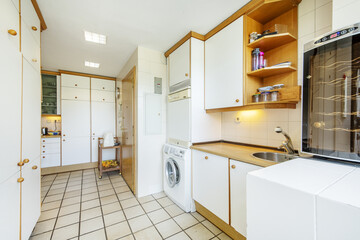 Kitchen with white wooden cabinets with wooden ball handles, a drinks fridge and square tiled floors