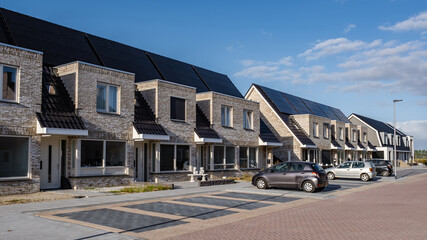 Newly build houses with solar panels attached on the roof against a sunny sky, housing market in...