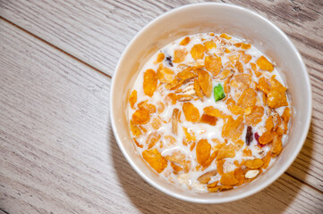 Healthy food - corn flakes in a white bowl on wooden background.