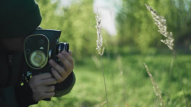 A man shoots spikelets of grass on an old movie camera. Close-up shooting