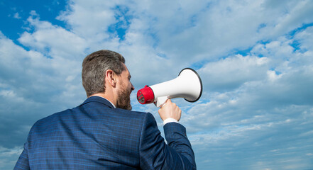 back view of businessman shout in loudspeaker on sky background. promotion