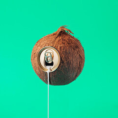 Coconut can spilling milk. Square and simple composition of a fruit on the pastel green background.
