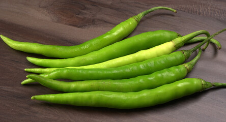 Fresh long Indian green chillies on wooden background.