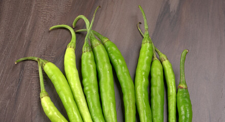 Fresh long Indian green chillies on wooden background.