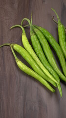 Fresh long Indian green chillies on wooden background.