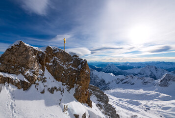 Panoramic view of the “Zugspitze“ (2962 m). highest peak of Germany and part of the “Wetterstein“ mountain range near Garmisch-Partenkirchen. Golden summit cross in alpine winter scenery in December.
