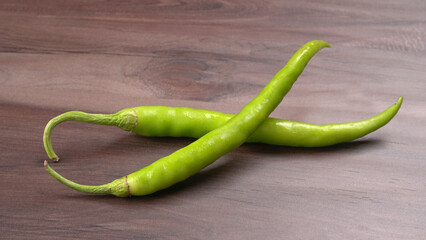 Fresh long Indian green chillies on wooden background.