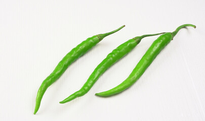 Fresh long Indian green chillies on wooden background.
