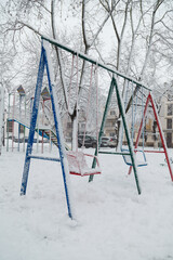 Bright colorful children playground covered with snow on winter snowy background. Snowfall weater, blizzard or snowstorm