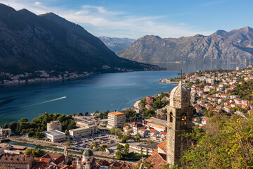 Fototapeta na wymiar Panoramic view from Kotor city walls on Church of Our Lady of Remedy and Kotor bay in sunny summer, Adriatic Mediterranean Sea, Montenegro, Balkan Peninsula, Europe. Fjord winding along coastal towns