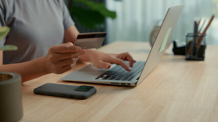 Asian woman holding credit card and using laptop for shopping online.
