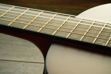 Obraz premium A guitars strings on the fretboard and a part of wooden acoustic board