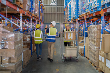 2 Staff in large depot storage warehouse manager and trainee walking check goods on shelf and radio