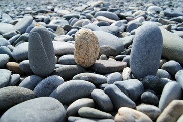 Three vertically placed stones on a rocky beach.