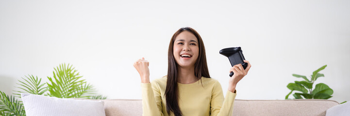 Asian Woman playing video games at home. .Cheerful gamer playing online games with console