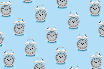 Trendy clock pattern made with white retro alarm clock isolated on pastel blue background.