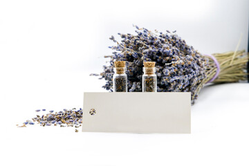 lavender seeds in two glass bottles with a sprig of lavender on a white background with a sign