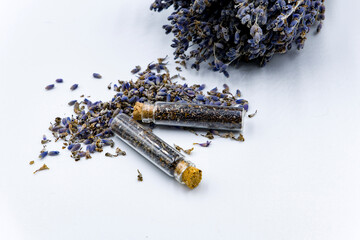 lavender seeds in two glass bottles with a sprig of lavender on a white background with a sign
