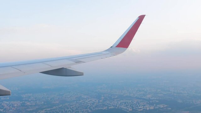 Airplane wing on city background, view from the porthole in flight. Travel and tourism concept. Comfortable flight