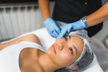 Obraz na płótnie Canvas High angle shot of a woman laying down with her eyes open and receiving a collagen injection. Beauty treatment. Aesthetic medicine concept. Beauty concept. High quality photo