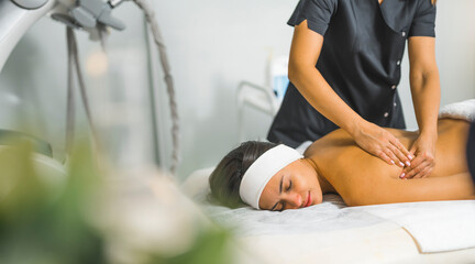 Obraz premium Side view of a woman laying down and being massaged. Blurred foreground. Beauty concept. Spa concept. High quality photo