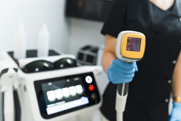 Close-up shot of a laser hair removal device held by a beautician. Blurred background. Beauty...