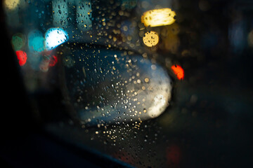 Fototapeta na wymiar Close-up view of a car's side mirror in the rain at night. High quality photo