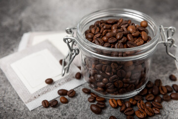 Drip coffee bag and coffee beans, ground coffee for brewing in a cup on a black marble background.Filter for drip coffee. Flatley. Copy space. Place for text.