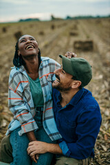 Shot of an affectionate couple sitting together on a farm field. Black woman and a caucasian man...