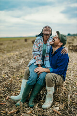 Shot of an affectionate couple sitting together on a farm field. Black woman and a caucasian man...