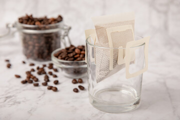 Making drip coffee with a special taste against the background of coffee beans. Drip coffee bag in a coffee cup. Trends in brewing coffee at home.Drip coffee filter. Flatley. Copy space. Place for tex