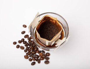Drip coffee bag with ground coffee for brewing in a cup isolated on white background.