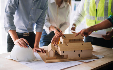  Scale model house on table with architects. Two architects making architectural model in office together.