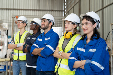 Group of robotic engineers wear helmets safety standing and arms crossed at factory workshop. Technician professional team robot arm welding machine.
