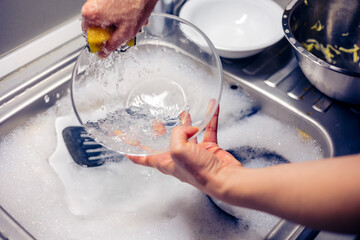 Close up of woman housewife is doing the dishes at home kitchen by using wash sponge and dishwashing